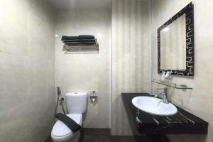 a bathroom with a toilet and a sink and a mirror at D'merlion Hotel Batam in Pembunuh +26 photos