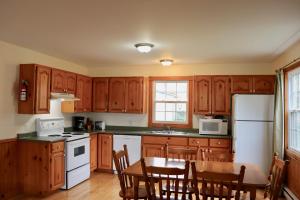 a kitchen with wooden cabinets and a table and a refrigerator at Shining Waters - Ingleside Cottages in Cavendish