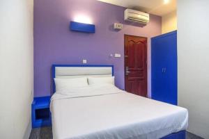 a bedroom with a white bed with a purple wall at D'merlion Hotel Batam in Pembunuh
