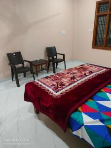 a bedroom with chairs and a bed with a colorful bedspread at Saraswati homestay in Ayodhya
