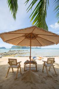 a table and two chairs under an umbrella on a beach at Morgan Villas in El Nido