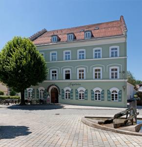 un gran edificio con un árbol delante en Hotel Angerbräu en Murnau am Staffelsee