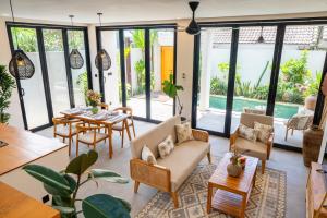 a living room with tables and chairs and windows at Villa Hati 2 in Canggu