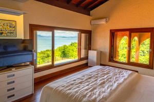 a bedroom with a bed and a large window at Mansão VOAR in Florianópolis