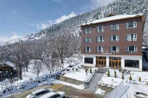 帕哈尔加姆Hotel Sparrow的一座建筑物,里面的汽车停在雪地前