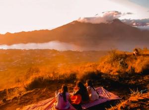 a group of girls sitting on a blanket looking at a mountain at Ayra Batur Sunrise Jeep in Kubupenlokan