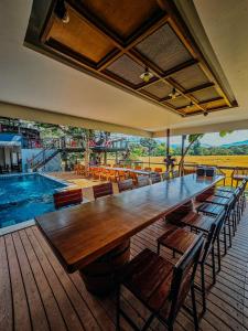 un grande tavolo in legno con sedie accanto alla piscina di พูลวิลล่าเชียงใหม่ บ้านดำวัวแดง a Ban Mae Pha Haen