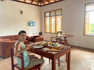 タンガラにあるMargosa villaの居間のテーブルに座る男