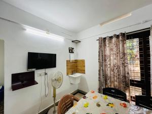 a room with a dining table and a tv on the wall at Alappattu meadows in Kottayam