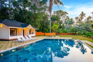 a villa with a swimming pool in front of a house at Fragrant Nature Backwater Resort & Ayurveda Spa Kollam in Kollam