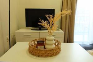 a basket with a vase on a table with a television at Cozy resort with free parking in CBD in Adelaide