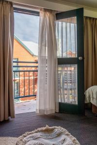 a bedroom with a window with a bed and a balcony at Cozy resort with free parking in CBD in Adelaide