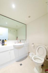 a bathroom with a toilet and a sink and a mirror at Cozy resort with free parking in CBD in Adelaide