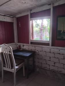a table and a chair in a room with a window at teriang minimal room in Pantai Kok
