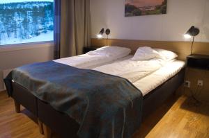 ein großes Bett mit einer Decke darüber in der Unterkunft Hamarøy Hotel in Innhavet