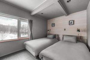 Un dormitorio con dos camas y una ventana en The Elysian Retreat, en Otaru