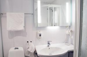 a white bathroom with a sink and a toilet at Hamarøy Hotel in Innhavet +15 photos
