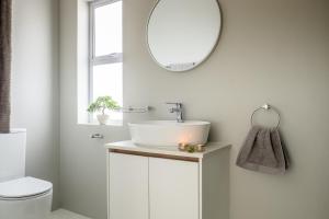 a white bathroom with a sink and a mirror at Perlemoentjie in Britannia Bay +24 photos