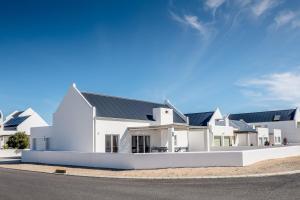 a white house with a black roof at Perlemoentjie in Britannia Bay