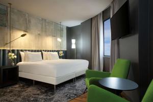 a bedroom with a white bed and a green chair at NH Collection Buenos Aires Jousten in Buenos Aires
