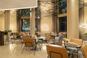 a restaurant with tables and chairs and windows at NH Collection Buenos Aires Jousten in Buenos Aires