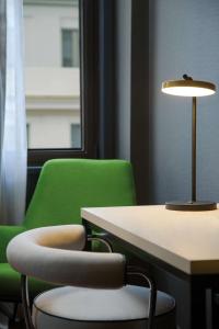 a green chair and a table with a lamp at NH Collection Buenos Aires Jousten in Buenos Aires