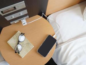 a table with glasses and a cell phone on a bed at Comfort Hotel Tokyo Kanda in Tokyo