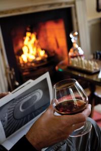 a person holding a glass of wine in front of a fireplace at Newforge House in Moira