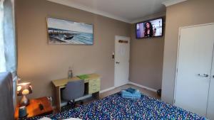 a bedroom with a bed and a desk and a monitor at Monique's AirCon Rm Prvt BthRm TV in Auckland