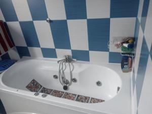eine weiße Badewanne in einem Zimmer mit blauen und weißen Fliesen in der Unterkunft Leonardo GuestHouse Available in Sibiu + 7 Fotos