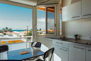 a kitchen with a table and chairs and a balcony at Le Lagon Vert in Saint-François