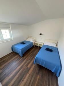 two beds in a room with wooden floors at Apartman Surya Medulin in Medulin