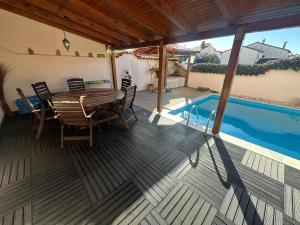 a wooden deck with a table and chairs next to a swimming pool at Apartman Surya Medulin in Medulin