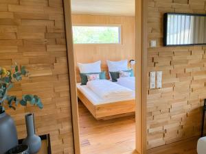 a bedroom with a bed in a wooden wall at Beim Dorfbach - Die Hofchalets in Kressbronn am Bodensee +28 photos