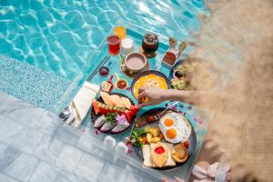 a table with breakfast food next to a swimming pool at Seabed Grand Hotel Phuket in Phuket