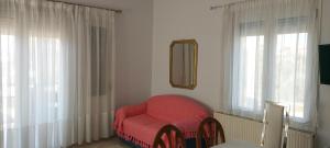 a red chair sitting in a room with windows at Billy's apartments in Artemida