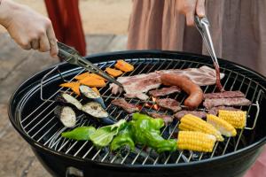 a person cooking meat and vegetables on a grill at 本格貸切サウナの宿 つづやビレッジ in Minokamo