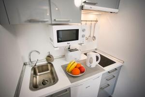 a small kitchen with a sink and a bowl of fruit at Corralejo Lodge in Corralejo