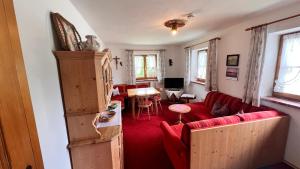a living room with a red couch and a table at Gästehaus Binderlehen in Schönau am Königssee