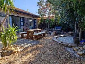 a patio with a wooden table and benches in a yard at Regent Casa's - Cape Towns Blouberg Area - Where 20 people can stay in Cape Town