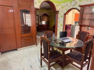 a kitchen with a glass table with a laptop on it at Shahgul's Service Apartments in Hyderabad
