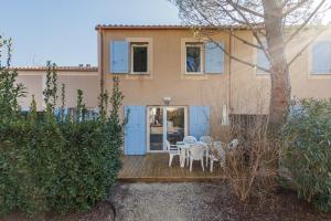 a house with a wooden deck with a table and chairs at Bastidon Provençal - Avec piscine partagée in Aubignan