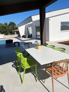 a patio with a white table and green chairs at Villa Cedrus in Juršići