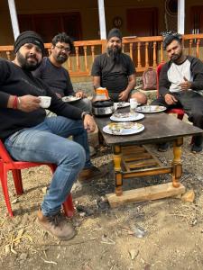 a group of men sitting around a table eating food at Magic Meadow Homestay in Shangarh +9 photos