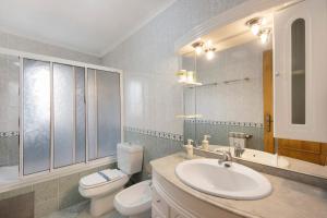 a bathroom with a sink and a toilet and a mirror at Xavega Apartment Torreira in Torreira