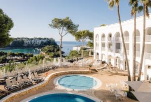 a view of the pool at a resort with palm trees and chairs at Comitas Floramar in Cala Galdana