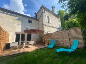 a patio with chairs and an umbrella in front of a house at Le Cast'L 2 Coin de paradis en bord de Dordogne in La Rivière