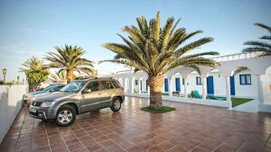 a car parked in front of a white house at Corralejo Lodge in Corralejo