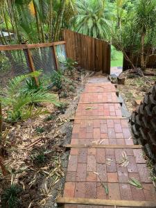 a brick path in a garden with a fence at Bushland View Retreat in Ocean Shores