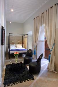 um quarto com uma cama, 2 cadeiras e uma mesa em Riad Dar Asam em Marraquexe